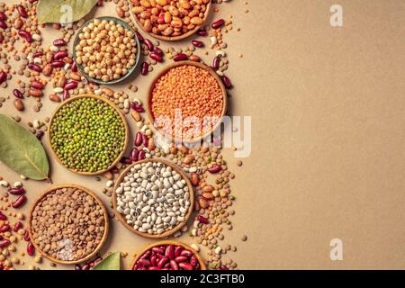 Legumes assortment, shot from above on a rustic brown background with copy space. Lentils, soybeans, chickpeas, red kidney beans Stock Photo