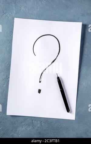 Question mark, written in ink on a piece of standard office paper, shot from above Stock Photo