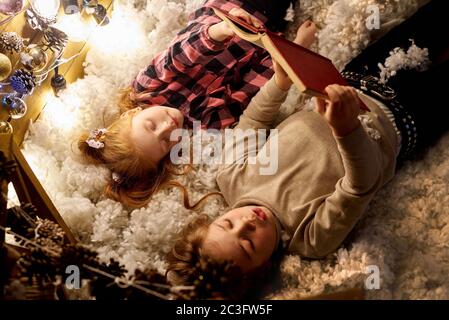 Children are reading a book in a decorated room for Christmas. Stock Photo