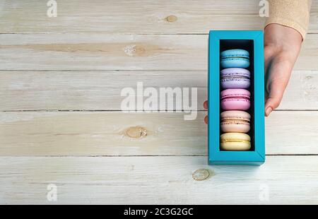 Female hand holds gift box with macaroons Stock Photo