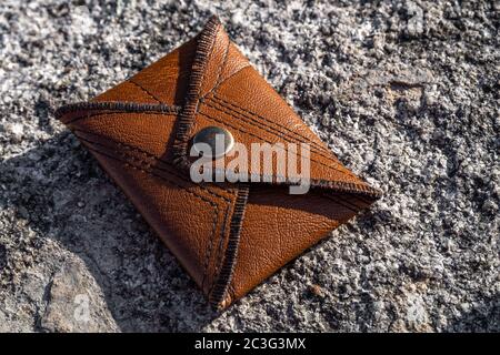 Handmade brown leather card wallet on stone background. Unisex accessory. Stock Photo