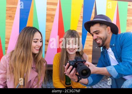A photographer smiles as he shows her a picture of two smiling girls Stock Photo