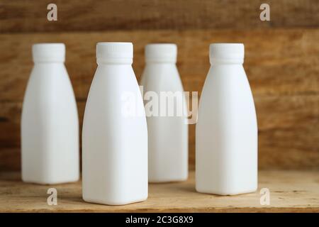 white plastic milk bottles on retro wooden table background Stock Photo