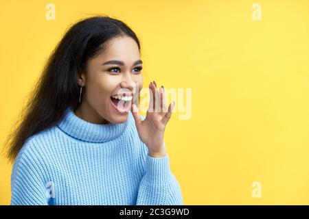 Young happy black woman shouting and screaming loud to side with hand on mouth Stock Photo