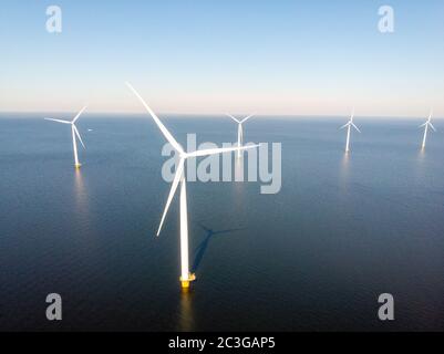 Windmill farm with colorful tulip fields in the Noordoostpolder netherlands, Green energy windmill turbine at sea and land Stock Photo