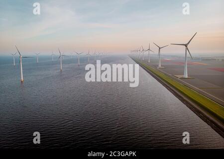 Windmill farm with colorful tulip fields in the Noordoostpolder netherlands, Green energy windmill turbine at sea and land Stock Photo