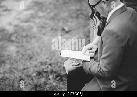 Top view grayscale of a couple sitting in a garden and lovingly reading a book together Stock Photo