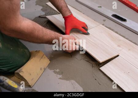 General construction worker. Adhesive for ceramic tiles. The builder glues terracotta to the floor. Stock Photo
