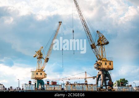 Two rusty abandoned cargo cranes in the city old industrial area Stock Photo
