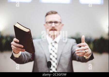 Selective focus shot of a male standing and holding a book in hands Stock Photo