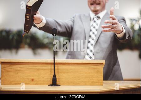 Selective focus shot of a male standing and holding a book in hands Stock Photo