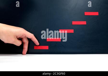 Ladder to success concept. Male fingers taking first step on a red staircase. Stock Photo