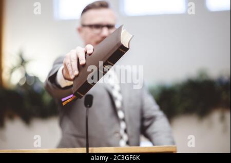 Selective focus shot of a male standing and holding a book in hands Stock Photo