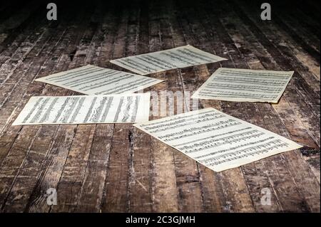 music sheets with notes of a musical work lie on the old floor in the dark Stock Photo