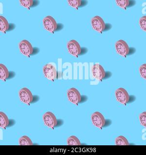 Pattern on a blue background of pink alarm clocks. Stock Vector