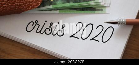 Crisis 2020 written on page of copybook and 100 Euro bills. Little money left, business bancruptcy concept Stock Photo