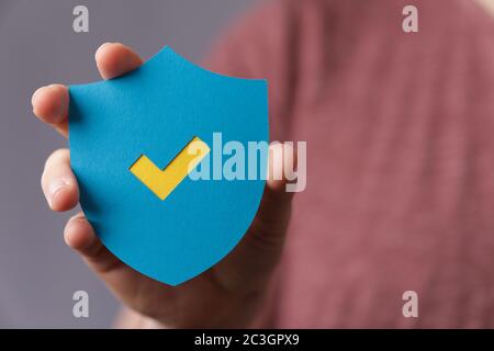 Man holding a protection shield with a checkmark Stock Photo
