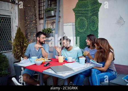 Group of young students taking a break from study with coffee and snacks Stock Photo