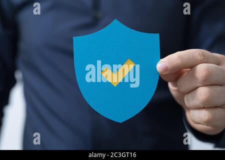 Man holding a protection shield with a checkmark Stock Photo