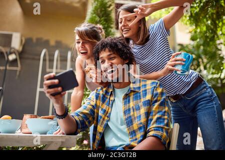 Friends taking a funny selfie at cafes's garden Stock Photo