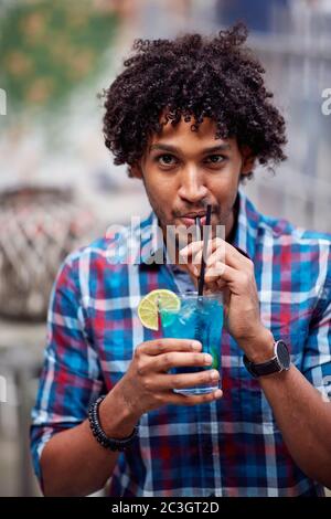 Photo portrait of young curly hispanic guy with cocktail Stock Photo