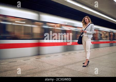 Businesswoman casually waiting for a metro transport on a station Stock Photo