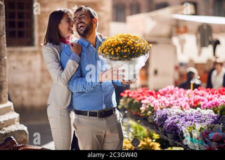 young happy caucasian couple in their honeymoon in italy, toscana, europe. Man is buying a bucket of flowers for his girlfriend Stock Photo