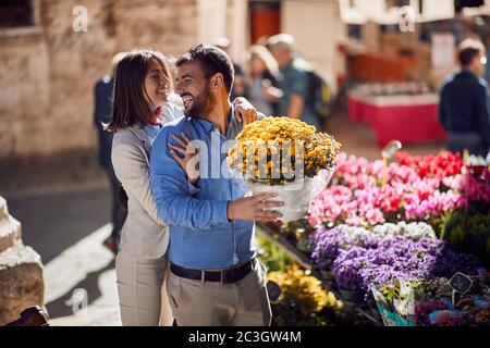 happy young couple in italy. Man is buying a bucket of flowers for his girlfriend Stock Photo