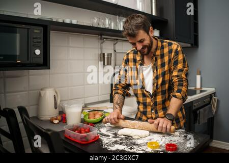 Young man is making cookies in his kitchen. Stock Photo