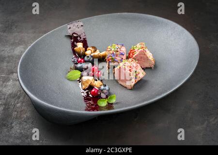 Fried dry aged venison tenderloin fillet medallion steak natural with mushrooms and forest berries as closeup on a modern design Stock Photo