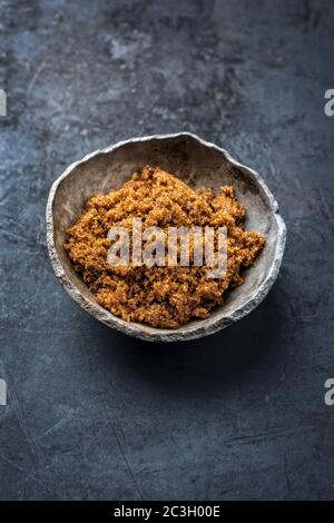 Traditional brown muscovado sugar offered as closeup in a rustic earthenware dish with copy space Stock Photo