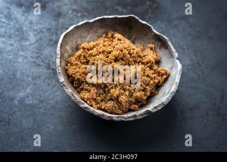 Traditional brown muscovado sugar offered as closeup in a rustic earthenware dish with copy space Stock Photo