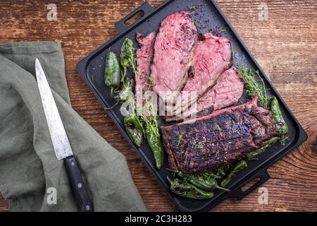 Traditional Commonwealth Sunday roast with sliced cold cuts roast beef with herbs and chili as top view on a modern design tray Stock Photo