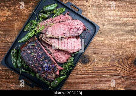 Traditional Commonwealth Sunday roast with sliced cold cuts roast beef with herbs and chili as top view on a modern design tray Stock Photo
