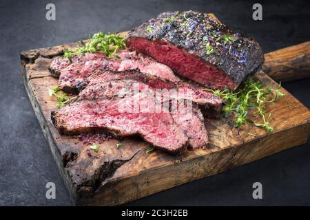 Traditional Commonwealth Sunday roast with sliced cold cuts roast beef with herbs and salt as closeup on a rustic wooden cutting Stock Photo