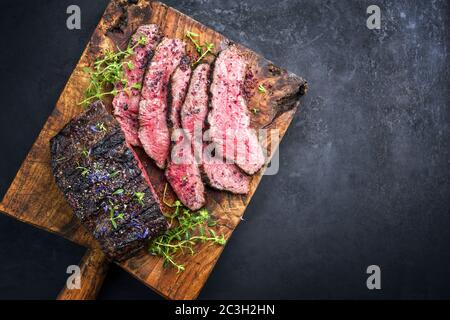 Traditional Commonwealth Sunday roast with sliced cold cuts roast beef with thyme and salt as top view on a rustic wooden cuttin Stock Photo
