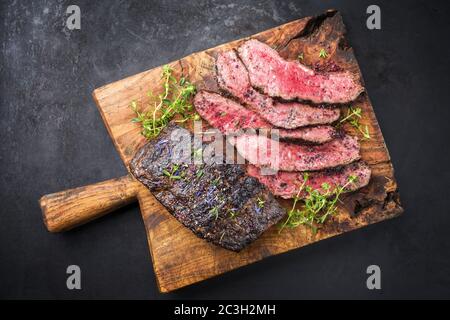 Traditional Commonwealth Sunday roast with sliced cold cuts roast beef with herbs and salt as top view on a rustic wooden cuttin Stock Photo