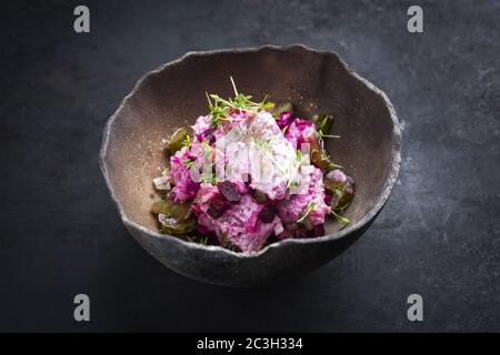 Traditional matie herring with beetroot salad and onion rings offered as closeup in a rustic modern design bowl with copy space Stock Photo