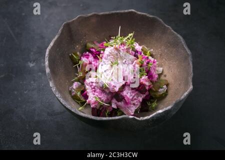 Traditional matie herring with beetroot salad and onion rings offered as closeup in a rustic modern design bowl with copy space Stock Photo