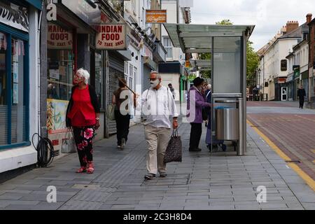 Ashford, Kent, UK. 20 June, 2020. Following the announcement by the government that non essential shops can open, the Ashford town centre high street appears busier than it has in the past few months of the Coronavirus pandemic during the first weekend of shops opening. Elderly couple wearing face masks in the high street. Photo Credit: Paul Lawrenson/Alamy Live News Stock Photo