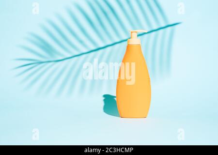 Orange container for lotion without label on blue background with leaf Stock Photo