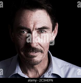 Low key portrait of a confident, mature man looking directly to the camera. Stock Photo