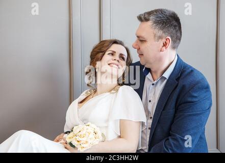 couple of newlyweds are sitting together looking at each other indoor with daylight Stock Photo