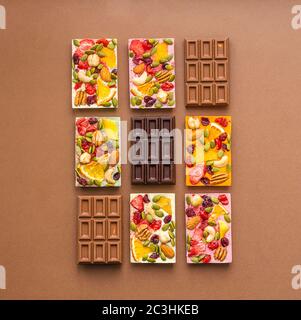 Chocolate of various colors and colored fillings with slices of fruit nuts on a brown background . Top view flat layout. Stock Photo