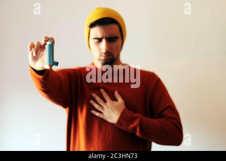 A selective focus shot of a male using a blue asthma inhaler to prevent an asthma attack Stock Photo