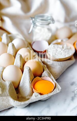 Baking ingredients with eggs, wheat flour, egg yolks for pastry. Cake, pasta or dough recipe ingredients. Top view on table