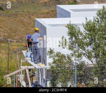 Facade Plaster On Exterior Wall. Posidonia: June 19th : Men on scaffold putting plaster on exterior house. Posidonia, June 19th,2020,Greece. Stock Photo