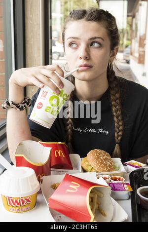 CANTERBURY, UNITED KINGDOM - Aug 29, 2019: Young Girl in Mcdonalds bored teenager with to much food drinking a milkshake Stock Photo