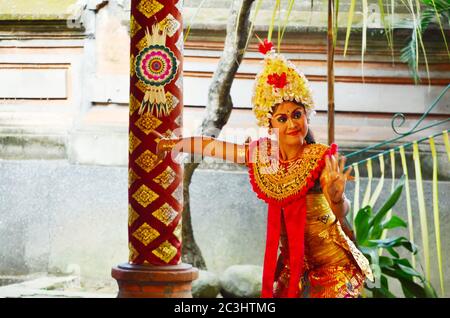 Beautiful woman dressed in colorful sarong, dancing traditional temple dance Legong at Bali Art and Culture Festival show. Stock Photo