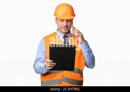 Repairman Worker Talking On Cellphone Holding Folder Standing In Studio Stock Photo